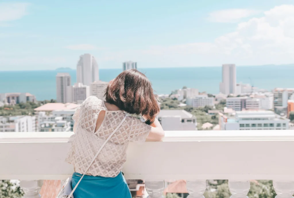 Woman looking over Pattaya city and the coastline from a high viewpoint