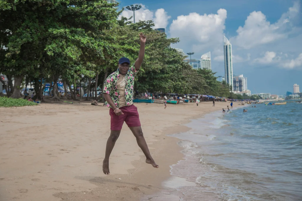 Jomtien Beach in Pattaya with a happy traveler relaxing on the sand and enjoying the ocean view.