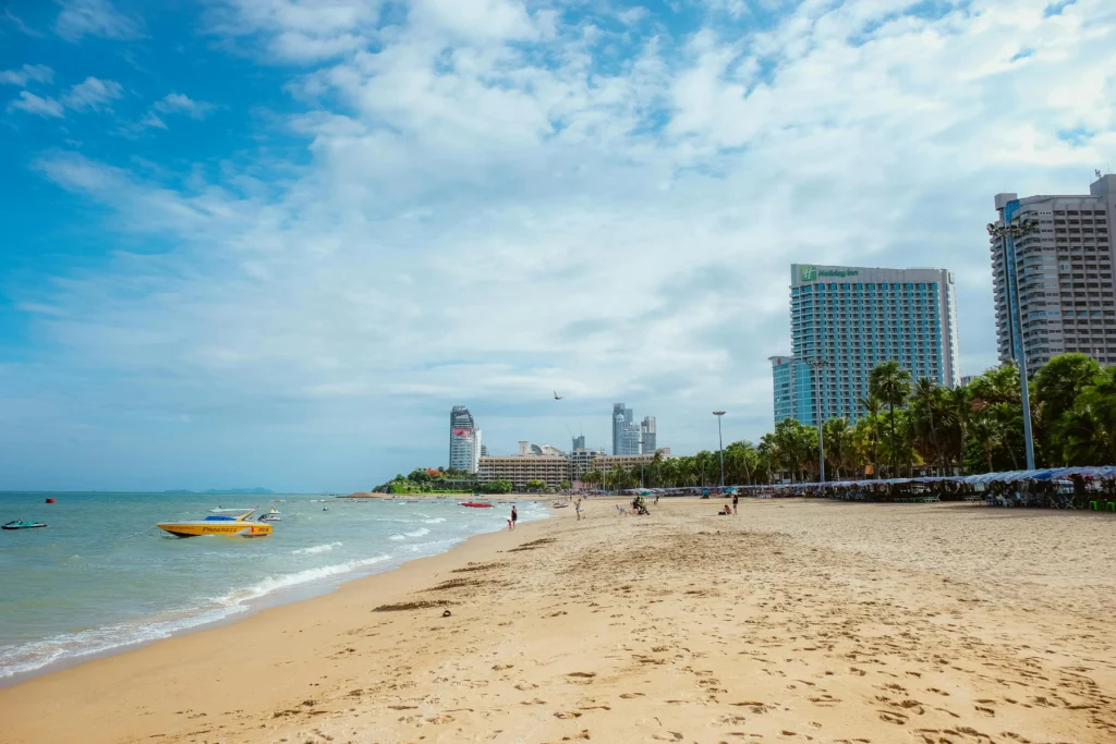 Pattaya beach shoreline with palm trees, soft waves and the city skyline in 2025.